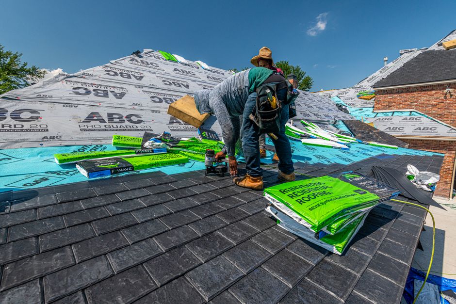 Professional roofer on residential home with modern safety equipment examining roof condition